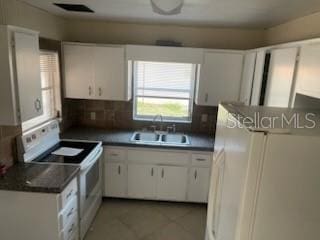 711A Pineland Ave, Venice, FL 34285 - kitchen with white appliances, a sink, white cabinetry, dark countertops, and backsplash