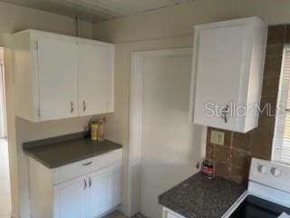 711A Pineland Ave, Venice, FL 34285 - kitchen featuring range, dark countertops, decorative backsplash, and white cabinetry
