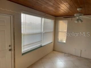 711A Pineland Ave, Venice, FL 34285 - spare room with wood ceiling, ceiling fan, plenty of natural light, and light tile patterned flooring