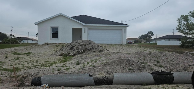 view of front of home with stucco siding, an attached garage, and driveway