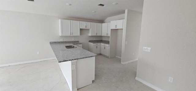 kitchen with stone counters, baseboards, lofted ceiling, and white cabinets