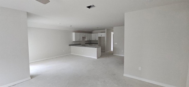 unfurnished living room featuring baseboards, ceiling fan, and unfinished concrete floors