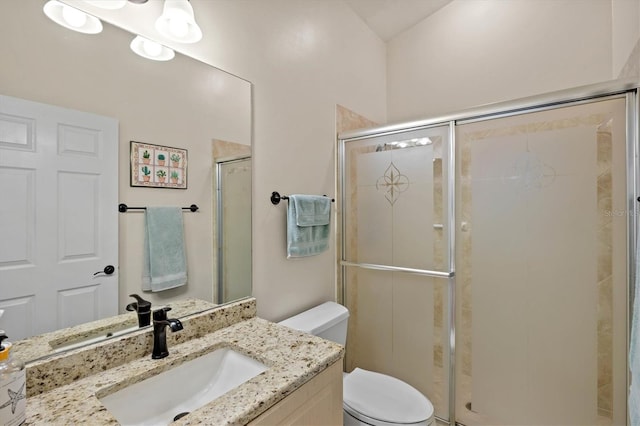 bathroom featuring toilet, a shower stall, and vanity