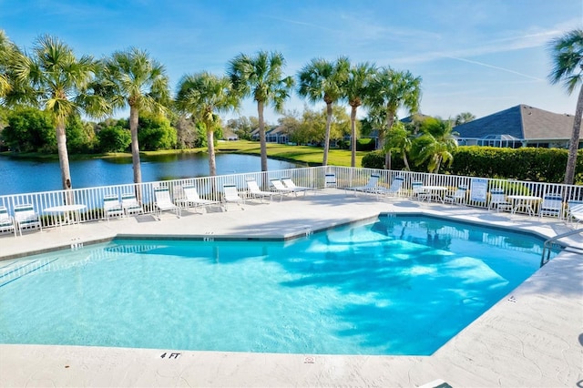 community pool with a patio area, fence, and a water view