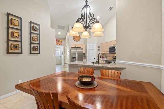 dining area with a high ceiling, visible vents, a chandelier, and light tile patterned flooring