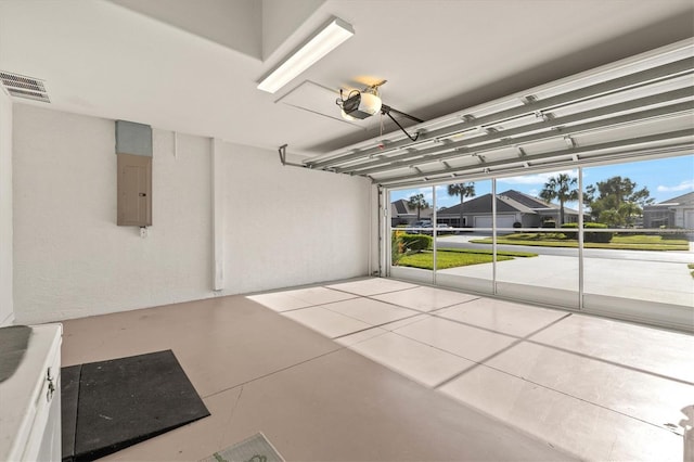 garage featuring electric panel, visible vents, and a garage door opener