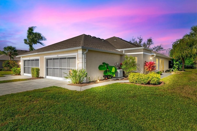 ranch-style home featuring a yard, central air condition unit, and a garage