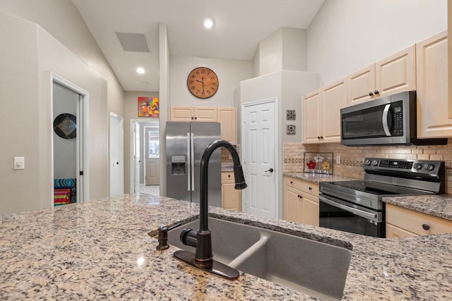 kitchen featuring visible vents, light stone counters, appliances with stainless steel finishes, a sink, and backsplash