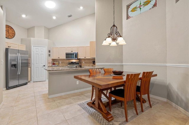 dining area with light tile patterned floors, recessed lighting, a notable chandelier, a high ceiling, and baseboards