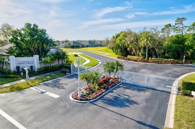 view of road featuring a gate, a gated entry, and curbs