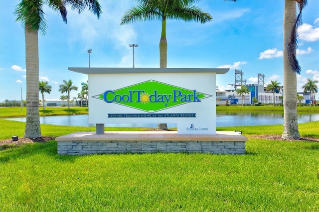 community sign featuring a water view and a yard