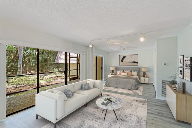 bedroom featuring access to exterior, a textured ceiling, and light hardwood / wood-style floors