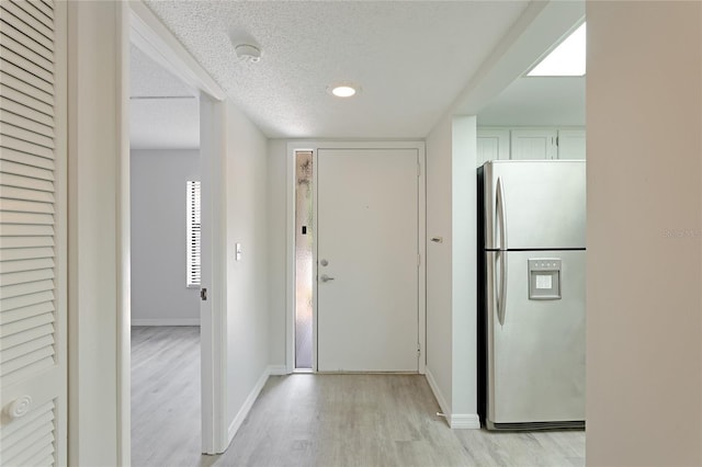 hallway with a textured ceiling and light wood-type flooring