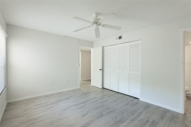 unfurnished bedroom with connected bathroom, ceiling fan, light hardwood / wood-style floors, a textured ceiling, and a closet