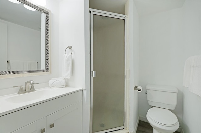 bathroom featuring hardwood / wood-style flooring, vanity, a shower with shower door, and toilet