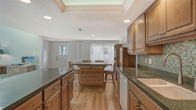 kitchen featuring ornamental molding, sink, light hardwood / wood-style floors, and a tray ceiling