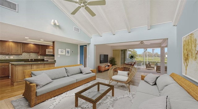 living room featuring beam ceiling, ceiling fan, high vaulted ceiling, and light hardwood / wood-style floors