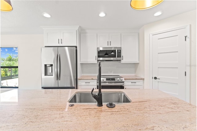 kitchen with light stone counters, backsplash, white cabinetry, and appliances with stainless steel finishes