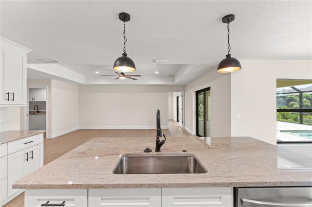 kitchen with decorative light fixtures, a tray ceiling, a wealth of natural light, and white cabinetry