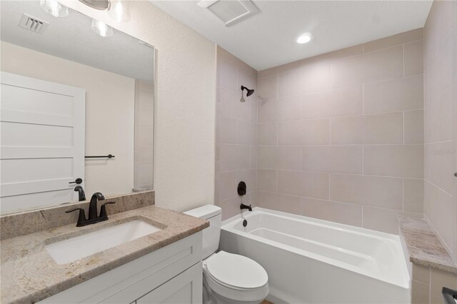 full bathroom featuring tiled shower / bath, vanity, and toilet