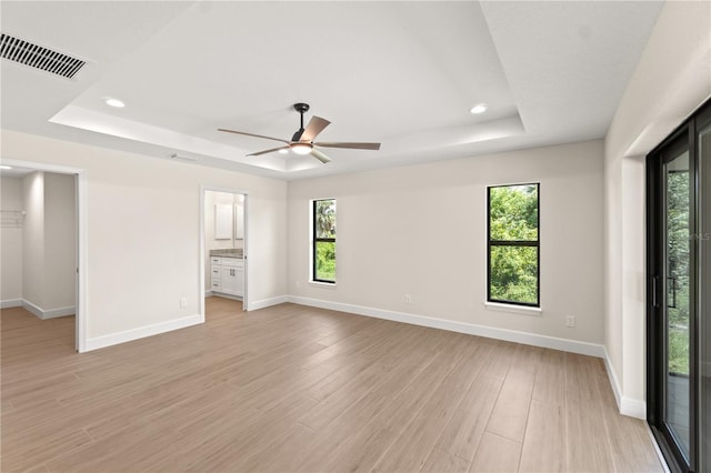 unfurnished room featuring ceiling fan, light hardwood / wood-style flooring, and a raised ceiling