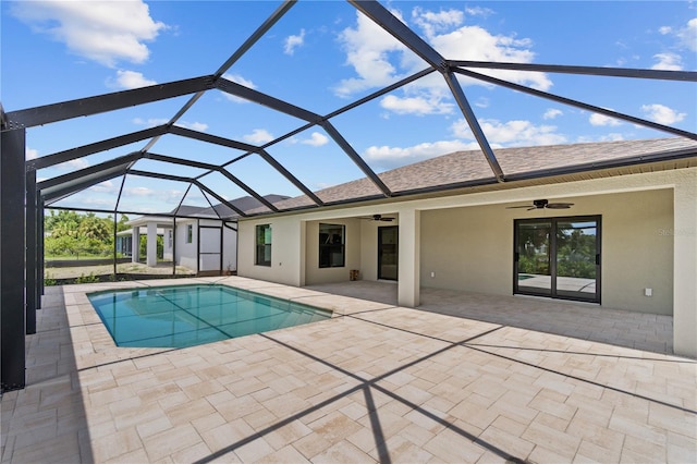 pool with a patio area, glass enclosure, and ceiling fan