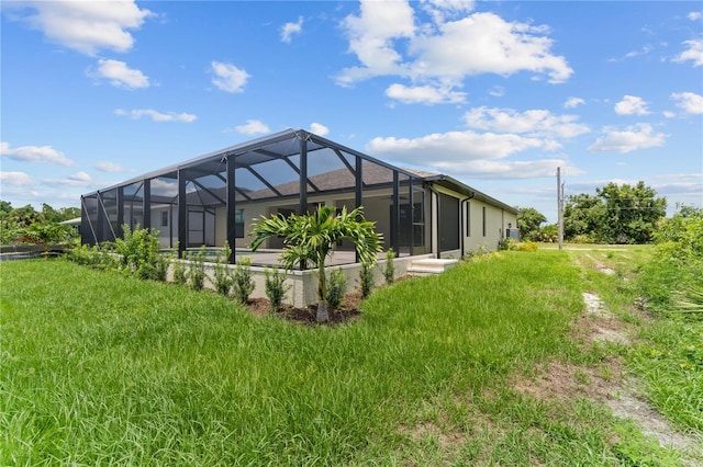 rear view of house with a lawn and glass enclosure