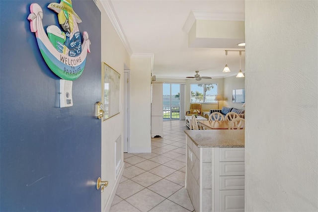 interior space featuring light tile floors, light stone counters, ceiling fan, and ornamental molding