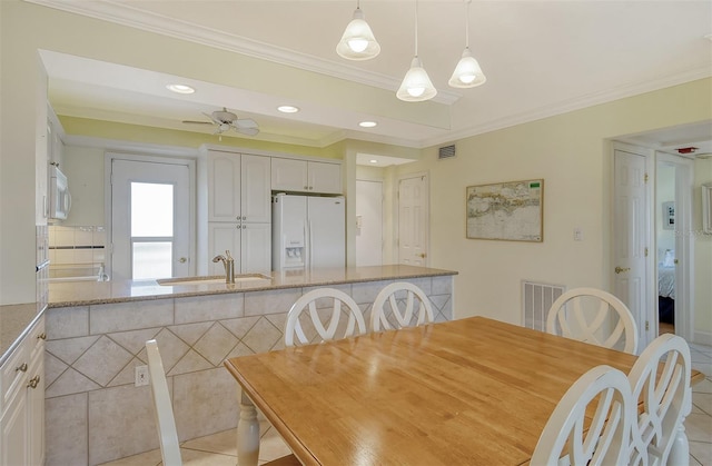 tiled dining space with crown molding, ceiling fan, and sink