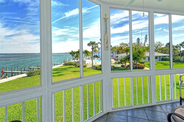 unfurnished sunroom featuring ceiling fan and a water view