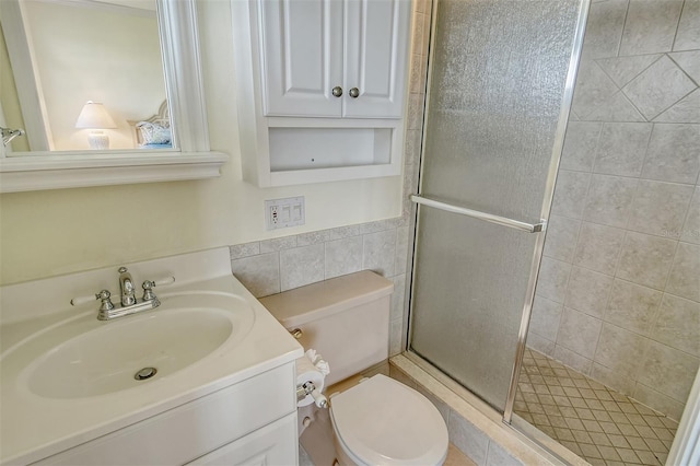 bathroom featuring tile walls, oversized vanity, toilet, and a shower with door