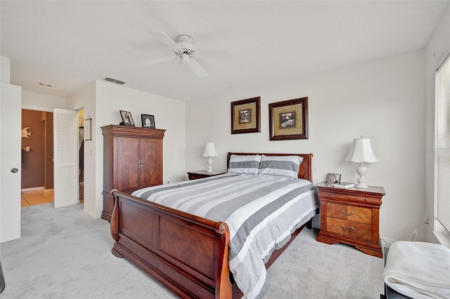 bedroom featuring a textured ceiling, ceiling fan, and light carpet