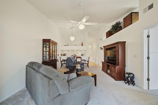 carpeted living room with ceiling fan and high vaulted ceiling