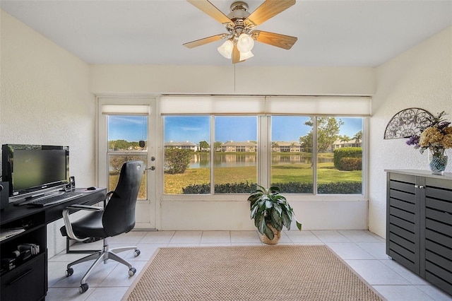 home office with a healthy amount of sunlight, ceiling fan, a water view, and light tile patterned floors