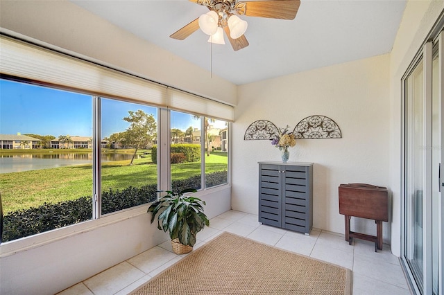 sunroom / solarium with ceiling fan and a water view