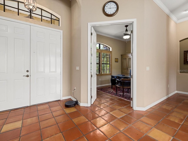 entrance foyer featuring a notable chandelier, dark tile flooring, and crown molding