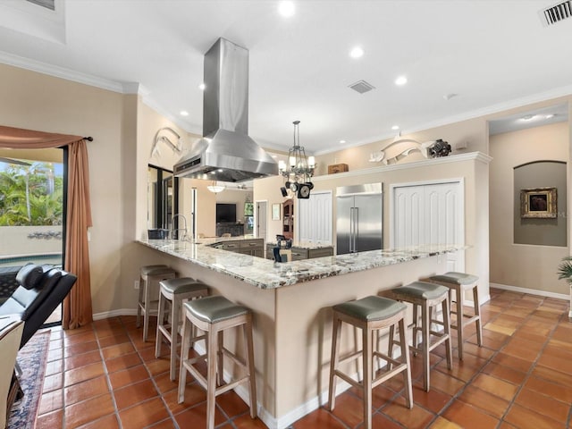 kitchen featuring a kitchen bar, tile flooring, stainless steel built in refrigerator, and island range hood