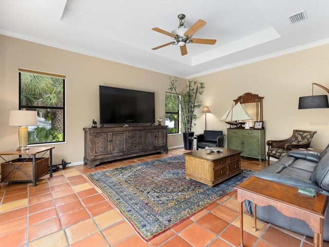 tiled living room with plenty of natural light, ornamental molding, ceiling fan, and a tray ceiling