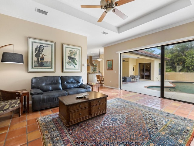 living room featuring a raised ceiling, tile floors, and ceiling fan