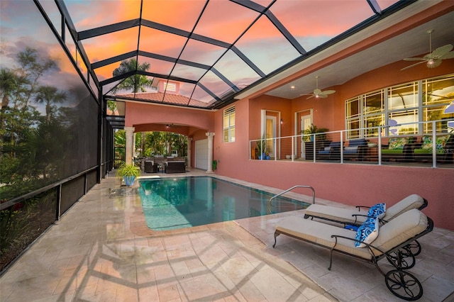 pool at dusk featuring a lanai, ceiling fan, an outdoor living space, and a patio area