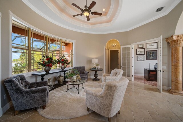 tiled living room with crown molding, ceiling fan, a tray ceiling, and ornate columns