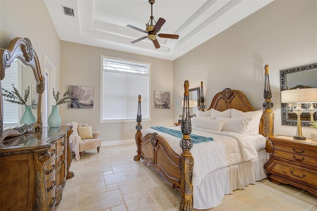 bedroom featuring light tile floors, a tray ceiling, and ceiling fan