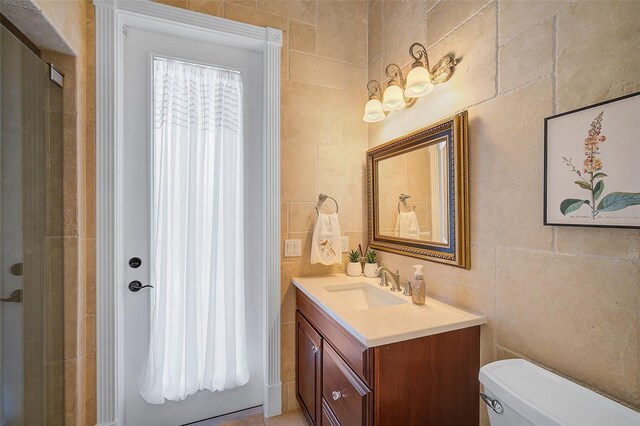 bathroom with tile walls, oversized vanity, and toilet