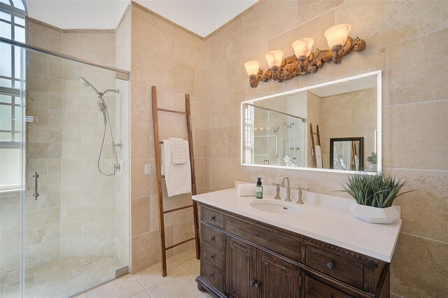 bathroom with a shower with door, plenty of natural light, large vanity, and tile walls