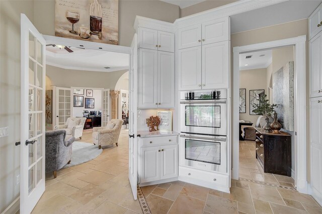 kitchen with french doors, ceiling fan, crown molding, white cabinets, and double oven