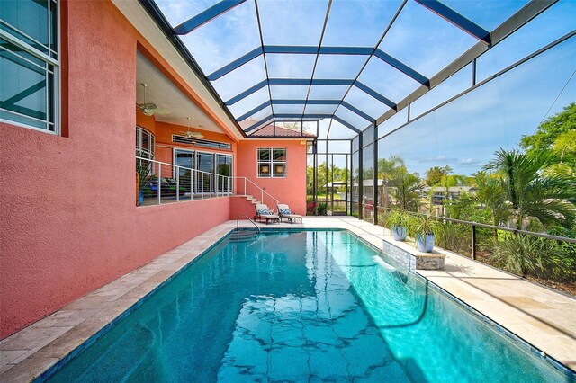 view of swimming pool featuring glass enclosure, ceiling fan, and a patio