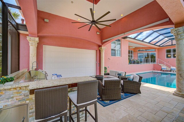 view of patio / terrace with a lanai, ceiling fan, and exterior kitchen