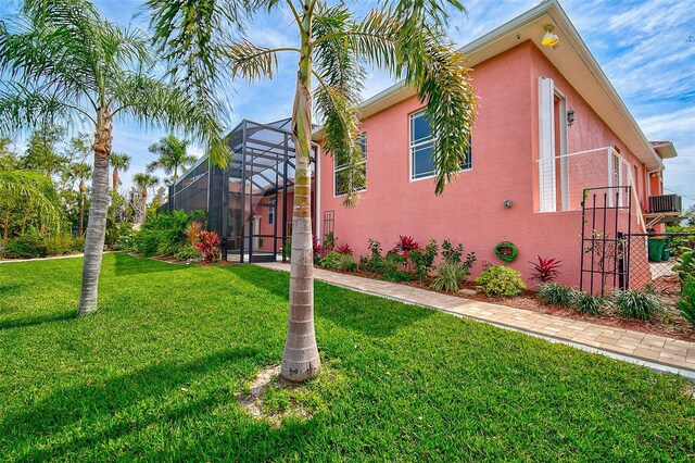 view of side of property with a lanai, central AC, and a lawn