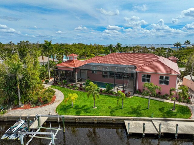 rear view of property with a water view, a lanai, and a lawn