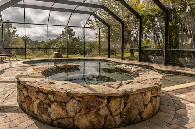 view of pool featuring glass enclosure, a patio area, and an in ground hot tub